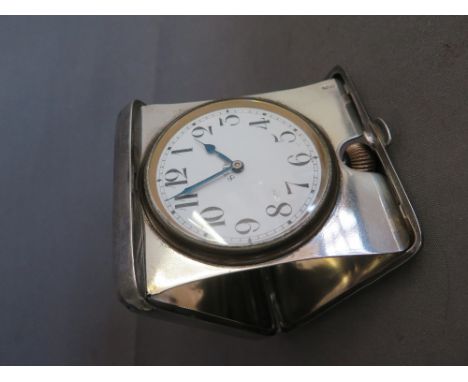 A silver cased Travelling clock - clock itself nickel - with white enamel face with Arabic numerals - Diameter of face 6 cm -