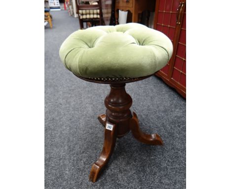 A buttoned cushion circular telescopic piano stool on tripod feet