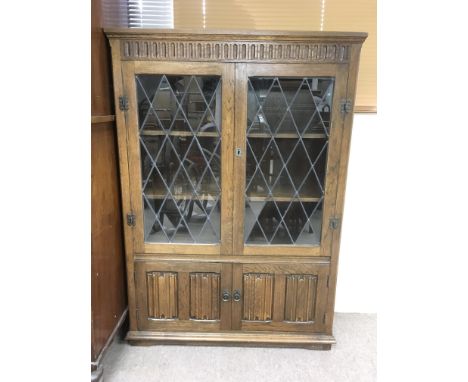 An oak bookcase with lead light glazed doors and two lower doors. Approximately 97cm wide x 31cm deep x 137cm tall.