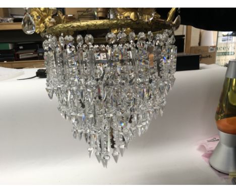 A five tier brass chandelier with cut glass drops.
