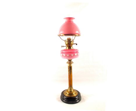 A Victorian Brass column oil lamp with pink glass bowl, cranberry shade and funnel