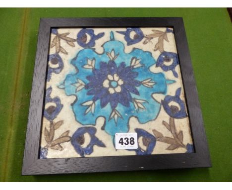 AN IZNIK TILE PAINTED WITH A BLUE STIPPLED FLOWER CENTRAL TO FLOWERING VINES, THE EBONISED FRAME.   23.5 x 23.5cms.