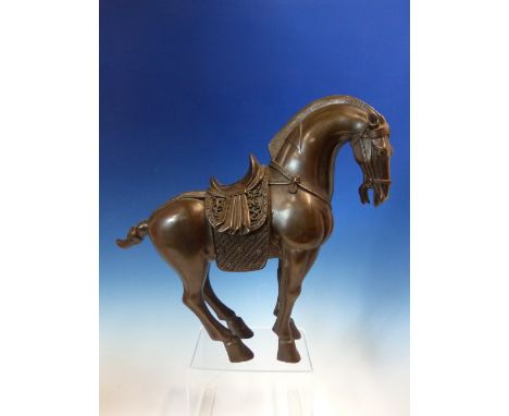 A CHINESE BRONZE HORSE CAST IN THE TANG STYLE WEARING A SADDLE AND BRIDLE.    H 32cms.