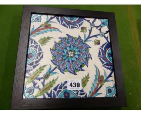 AN OTTOMAN STYLE KUTAHYA TILE, A TURQUOISE BORDERED BLUE FLOWER CENTRAL TO BUDS AND LEAVES, THE EBONISED FRAME.   25.5 x 25.5