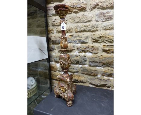 A GILT GESSO PINE CANDLESTICK, THE TRIPOD BASE CARVED IN BAROQUE STYLE WITH ANGELS HEAD BETWEEN THE BRACKET FEET.   H 59.5cms