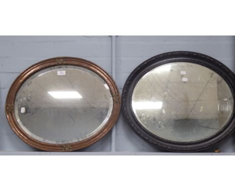 AN OVAL BEVELLED EDGE WALL MIRROR, in beaten copper cavetto frame, decorated with four heraldic roses, 16" x 22 1/2" and ANOT