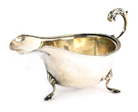 A Victorian silver sauce boat, with a reeded border and acanthus leaf scroll handle, on shell capped tripod feet, maker SB &a