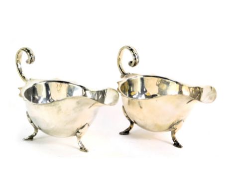 A pair of silver plated sauce boats, with fluted border and scroll capped handle, on tripod feet, bearing initials HHC, stamp