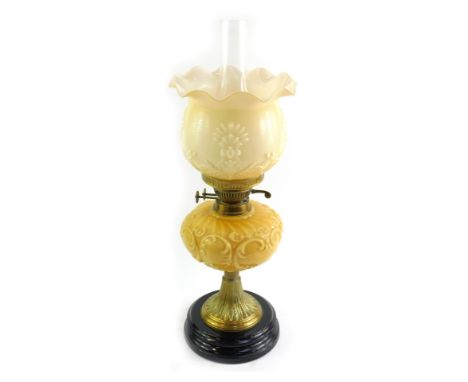 A late Victorian oil lamp, with opaque yellow glass reservoir, matching similar shade, and brass fittings and tapered brass c