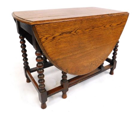 A 1920s oak oval gate leg table, with bobbin turned supports, flat stretchers, 73cm high, the top 102cm x 145cm (leaves up).