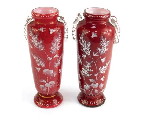 A pair of Victorian ruby glass two handled vases, with white enamel decoration depicting blooming branches along winged beetl