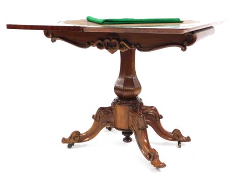 A Victorian mahogany turn over top card table, with green baize interior, the apron with applied carved scroll decoration on 