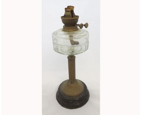 A Victorian Oil Lamp with brass fittings, clear glass font, brass column and a circular metal base, (lacks chimney or shade),
