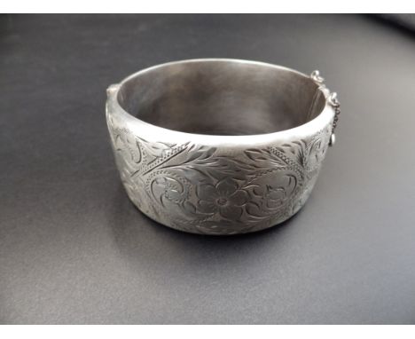 A silver hallmarked hinged bangle with safety chain (Birmingham 1966 by Ronex) 49.18g total weight.