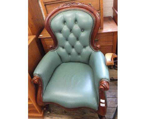 A mahogany button back armchair with green leather upholstery