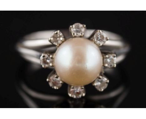 A cultured pearl and diamond circular cluster ring: the single cultured pearl approximately 7mm diameter within a surround of