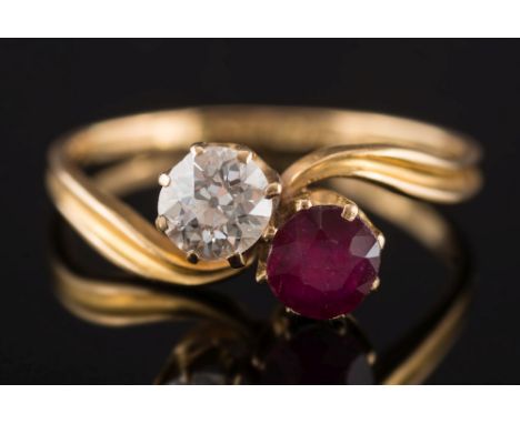 An 18ct gold, ruby and diamond two-stone cross over ring: claw set with a circular ruby and a an old-cut diamond estimated to