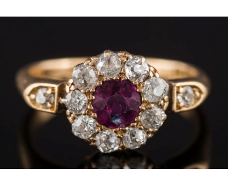 An Edwardian ruby and diamond circular cluster ring: the central round ruby approximately 0.50ct within a surround of old bri