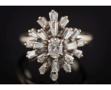 A diamond mounted cluster ring: with central oval diamond within a star-burst surround of tapering baguette-cut diamonds, rin