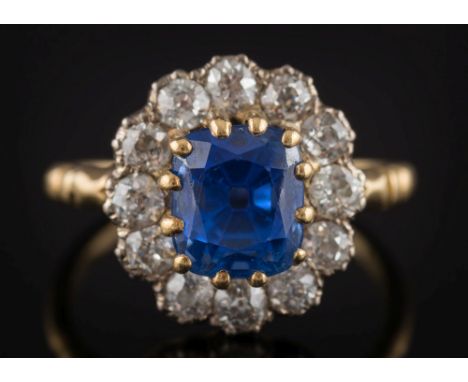 A cushion shaped sapphire and diamond cluster ring: with central cushion-shaped sapphire approximately 8.2mm long x 7.1mm wid