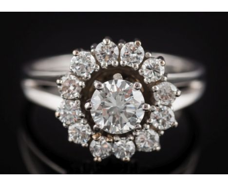 A diamond mounted circular cluster ring: with central round brilliant-cut diamond approximately 0.75ct within a surround of s