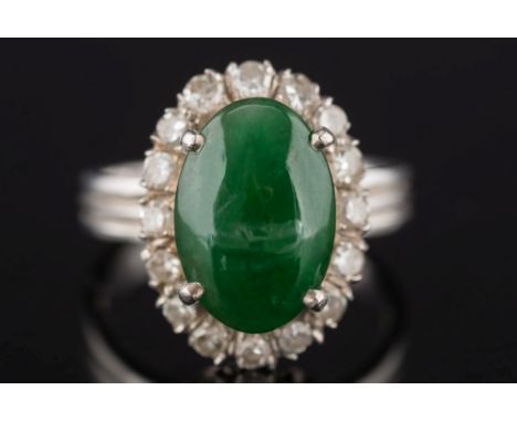 A jade and diamond oval cluster ring: the oval jade within a surround of single-cut diamonds, the shank stamped '18K', ring s