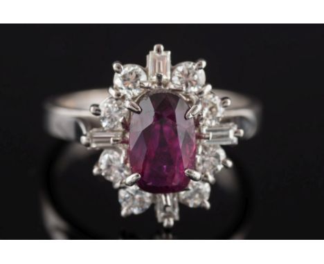 An 18ct white gold, ruby and diamond oval cluster ring: the central 'native-cut' oval ruby, approximately 8.3mm long x 5.5mm 