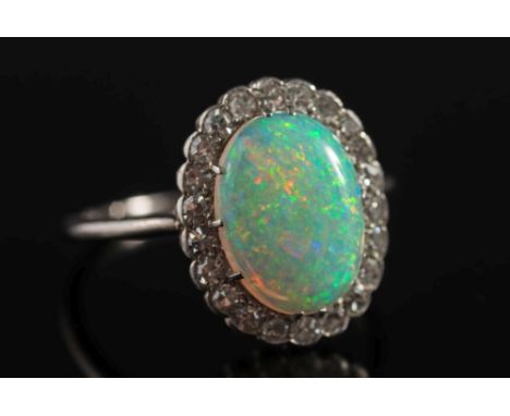 An opal and diamond oval cluster ring: the oval opal approximately 12.7mm long  x 9.7mm wide claw-set within a surround of si