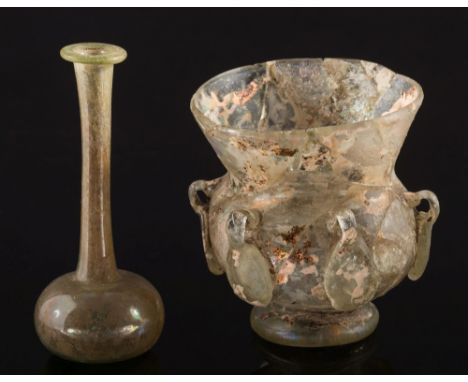A Byzantine pale green glass lamp and a Roman pale green glass unguentarium: the lamp with central wick-holder and applied fo