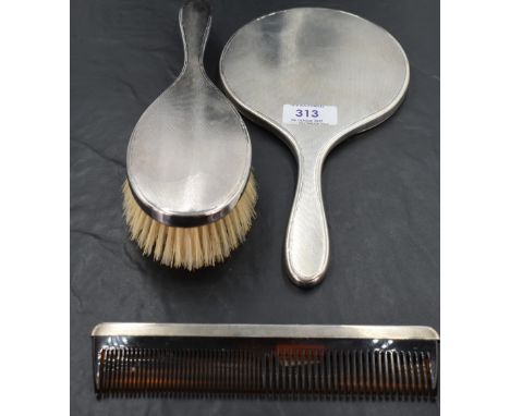 A 1960's silver three-piece dressing table set, comprising hand mirror, hair brush and comb of traditional design with engine