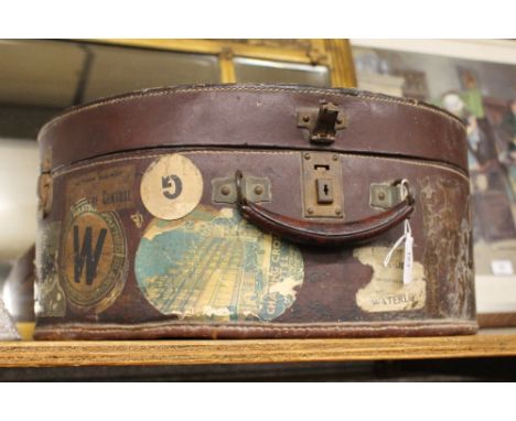 A vintage circular leather suitcase covered with numerous luggage labels