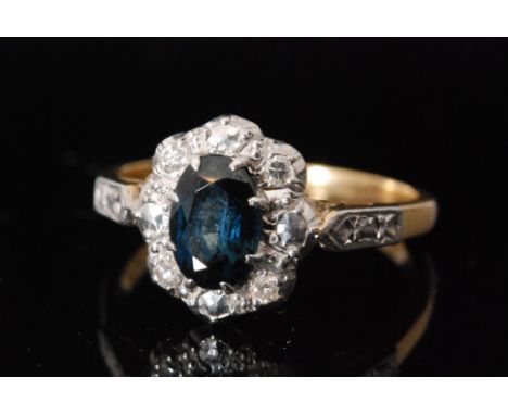 A mid 20th Century 18ct sapphire and diamond cluster ring, central oval sapphire within four stone diamond surround, ring siz