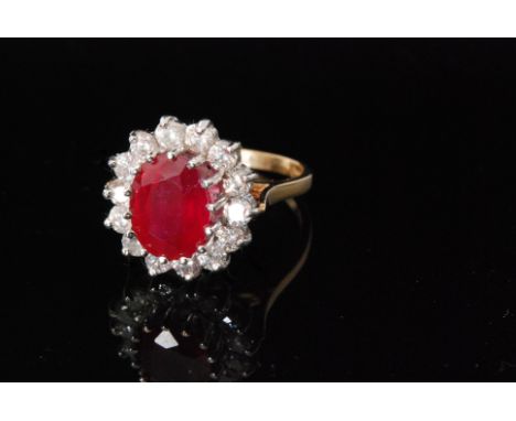 An 18ct hallmarked ruby and diamond cluster ring, central oval ruby within fourteen brilliant cut diamond surround, all stone