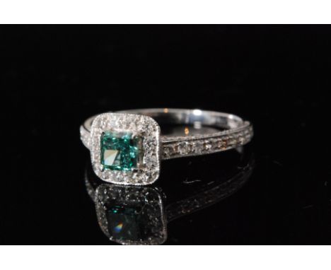 A contemporary 18ct white gold green and white diamond cluster ring, central square cut green diamond claw set within a twelv