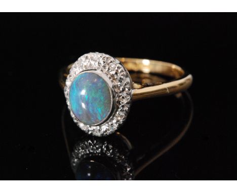 An 18ct opal and diamond cluster ring, central collar set opal within diamond surround to knife edged shoulders, ring size L 