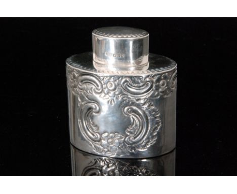 An Edwardian hallmarked silver tea caddy of ovoid outline with embossed floral and scrolling decoration below ovoid pull off 