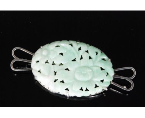 A carved and pierced pale green jade brooch, the oval shaped panel pierced and carved with chrysanthemum and foliage, claw se