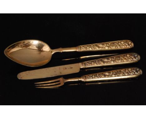 A George IV hallmarked silver gilt knife fork and spoon set, each with embossed shell and foliate decorated handle and contai