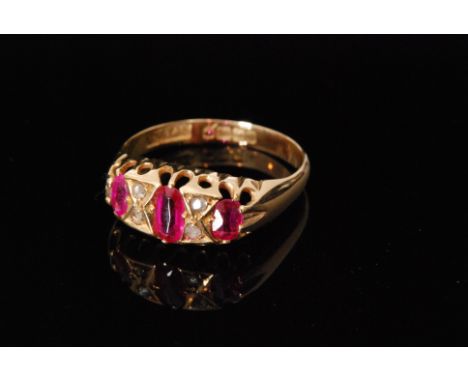 An early 20th Century 18ct hallmarked ruby and diamond seven stone boat shaped ring, three oval rubies spaced by two pairs of