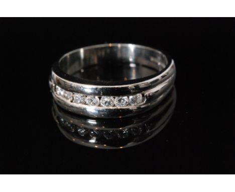 A contemporary 18ct hallmarked white gold diamond half eternity ring, comprising seven channel set brilliant cut stones, ring