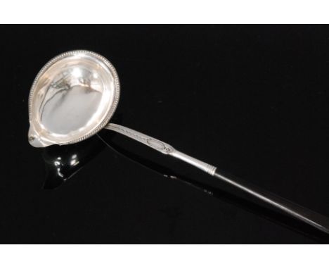 A George III hallmarked silver toddy ladle with beaded border and bright cut engraved decoration below twisted whale bone han