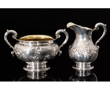 A Victorian hallmarked silver twin handled sugar bowl and matching pedestal cream jug, each with all over embossed and engrav
