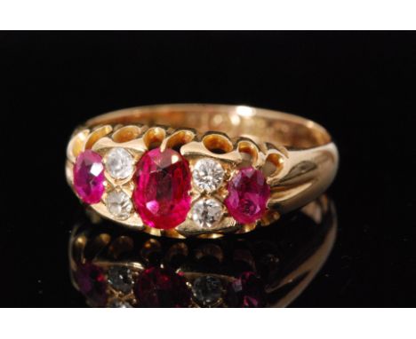 An Edwardian 18ct hallmarked seven stone ruby and diamond boat shaped ring, three rubies spaced by pairs of diamonds to reede