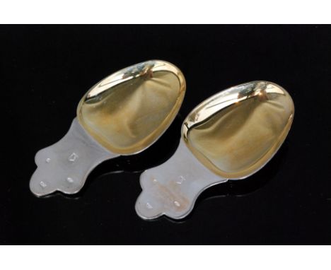 A pair of modern hallmarked silver caddy spoons each with wide oval gilt bowls below plain triform shaped handles, Birmingham