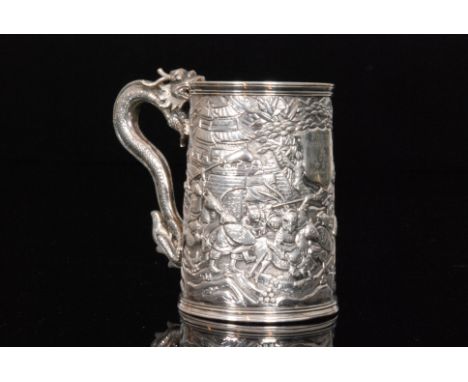 A late 19th Century Chinese silver small tankard profusely decorated with a battle scene and terminating in dragon scroll han