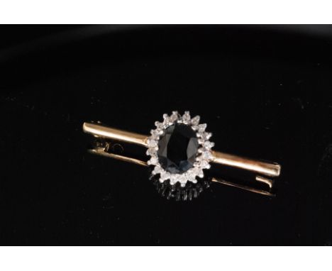 A 9ct hallmarked sapphire and diamond bar brooch, central oval sapphire within diamond surround, all stones claw set to a pla