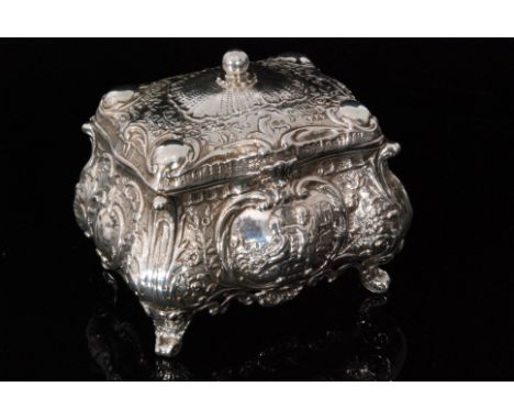 An early 20th Century German silver rectangular casket heavily embossed with foliate scrolls around central panel of two cher
