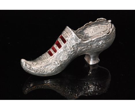 An Edwardian hallmarked silver pin cushion modelled as a lady's shoe decorated with embossed flowers, terminating in hinged c