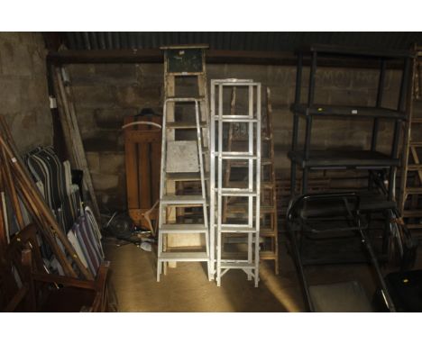 A quantity of various wooden and metal folding step ladders