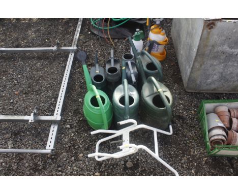 A quantity of plastic watering cans and a ladder stand off